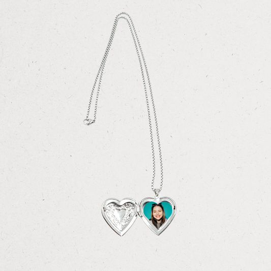 Heart-shaped locket with a photo on a light gray background