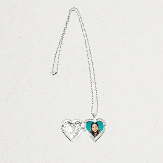 Heart-shaped locket with a photo on a light gray background