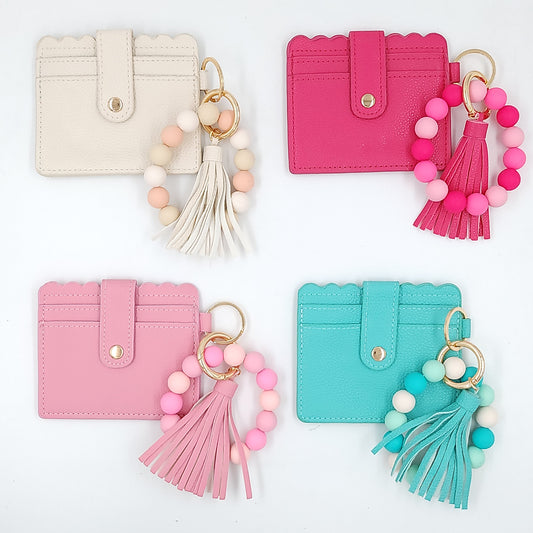 A collection of leather wallets for women in beige, pink, and blue colors, each with a different color tassel and keychain. Customized gifts for all occasions Amman Jordan