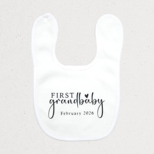 White bib with 'First grandbaby February 2026' text Baby shower personalized gift Amman Jordan