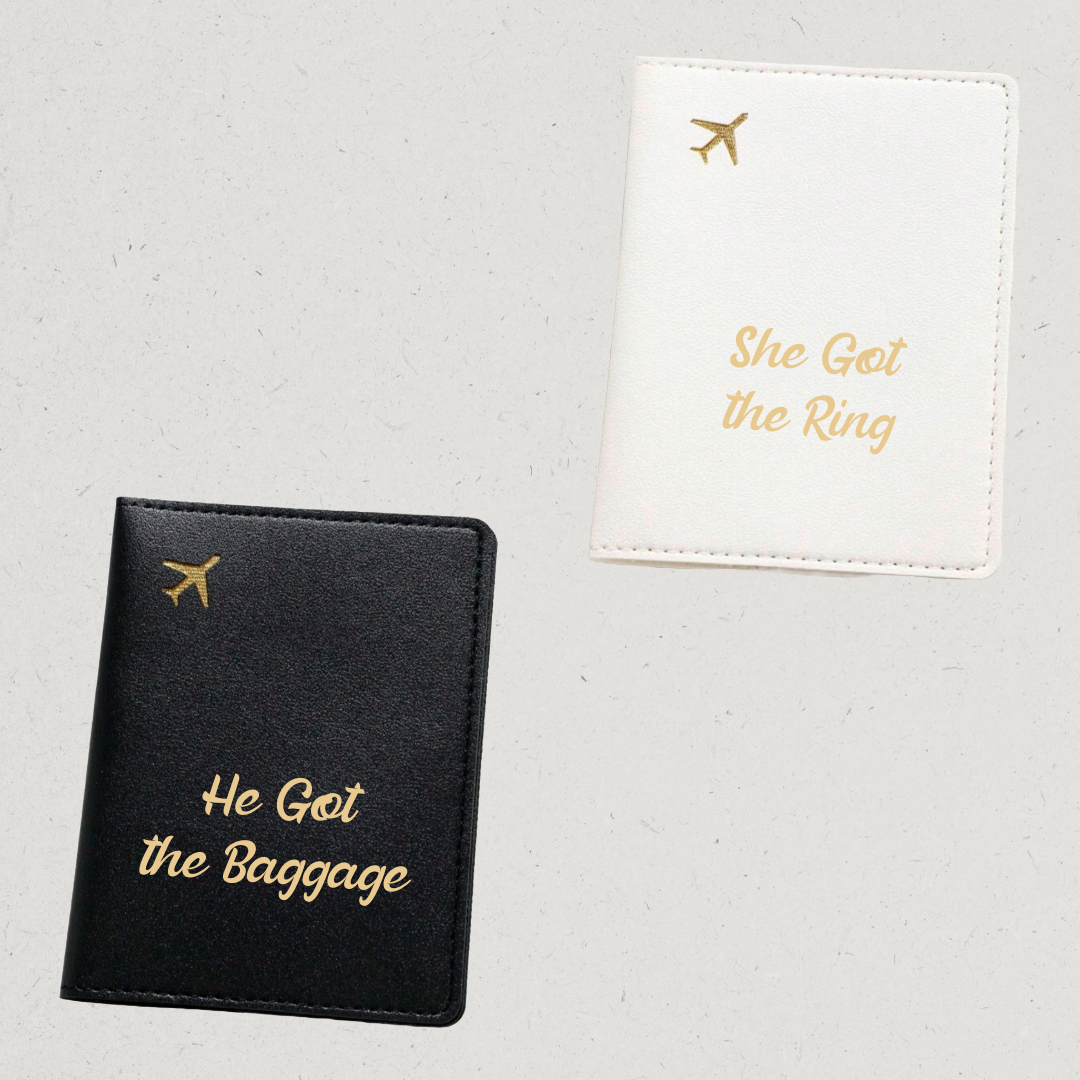 Black passport holder with 'He Got the Baggage' text and white passport holder with 'She Got the Ring' text