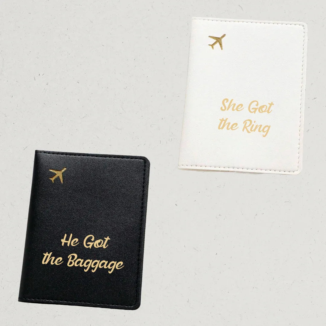 Black passport holder with 'He Got the Baggage' text and white passport holder with 'She Got the Ring' text