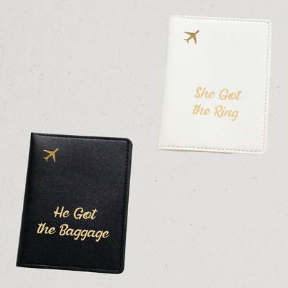 Black passport holder with 'He Got the Baggage' text and white passport holder with 'She Got the Ring' text 